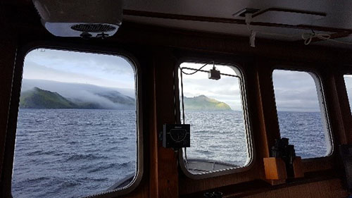 Dense fog rolling down the hillsides calm the waters inside the harbor.