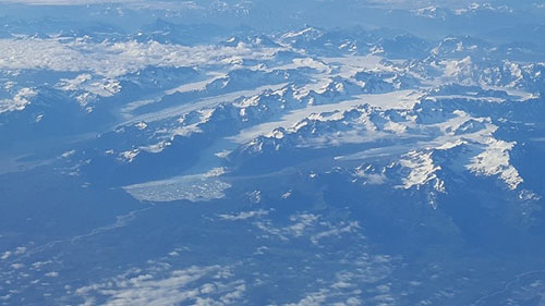 The view from my airplane window: snowy mountains and icy flows.