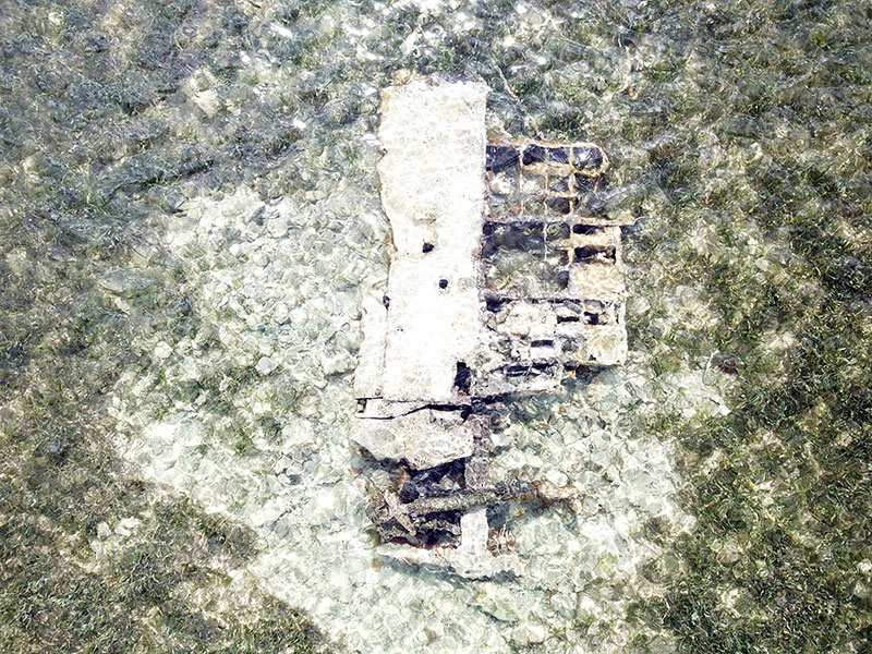 Aerial view of the aircraft wing at low tide in the lagoon. The landing strut is visible.