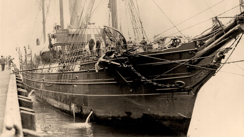Close-up of Bear mooring to a pier showing her hull and sail rig.