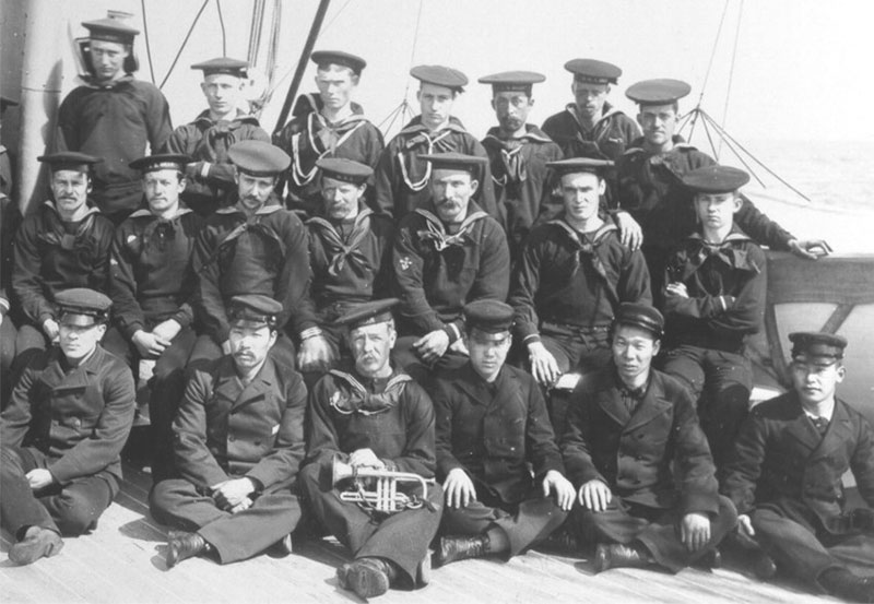 A posed crew photo on the deck of the Bear, including Asian enlisted men seated on bottom row.