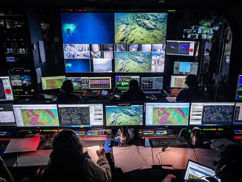 Expedition team members monitor a remotely operated vehicle dive in the control room on Exploration Vessel Nautilus.