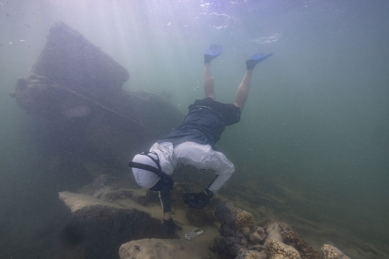 NOAA archaeologist Matthew Lawrence examining poured concrete ballast at an unidentified shipwreck site.