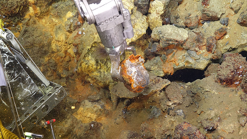 Woods Hole Oceanographic Institute's remotely operated vehicle Jason gathers a mineral sample from the seafloor at Escanaba Trough during the Escanaba Trough: Exploring the Seafloor and Oceanic Footprints expedition.