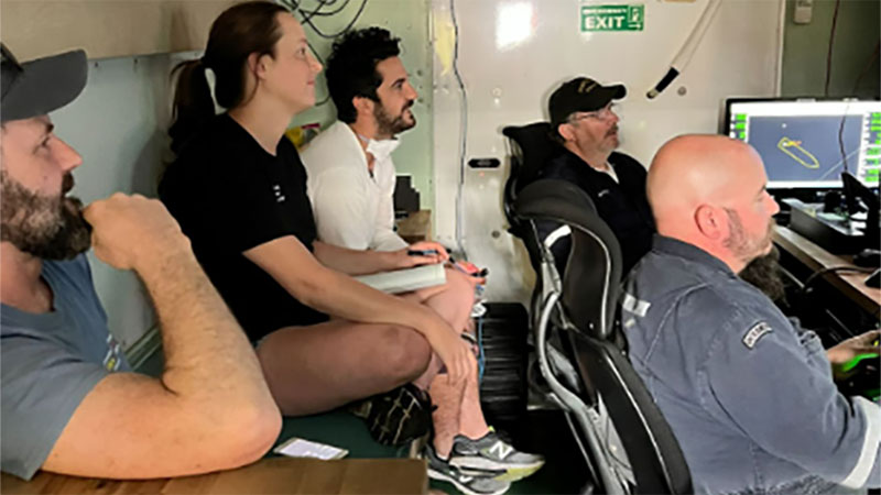 Foto tomada el 13 de abril de 2022. Madeline Evanson y Erik Cordes acompañan al equipo de ingeniería oceanográfica en la cabina de pilotaje del vehículo operado de forma remota, mientras observan y dirigen una inmersión de la expedición Exploración de la biodiversidad en las aguas profundas de Puerto Rico 2022.