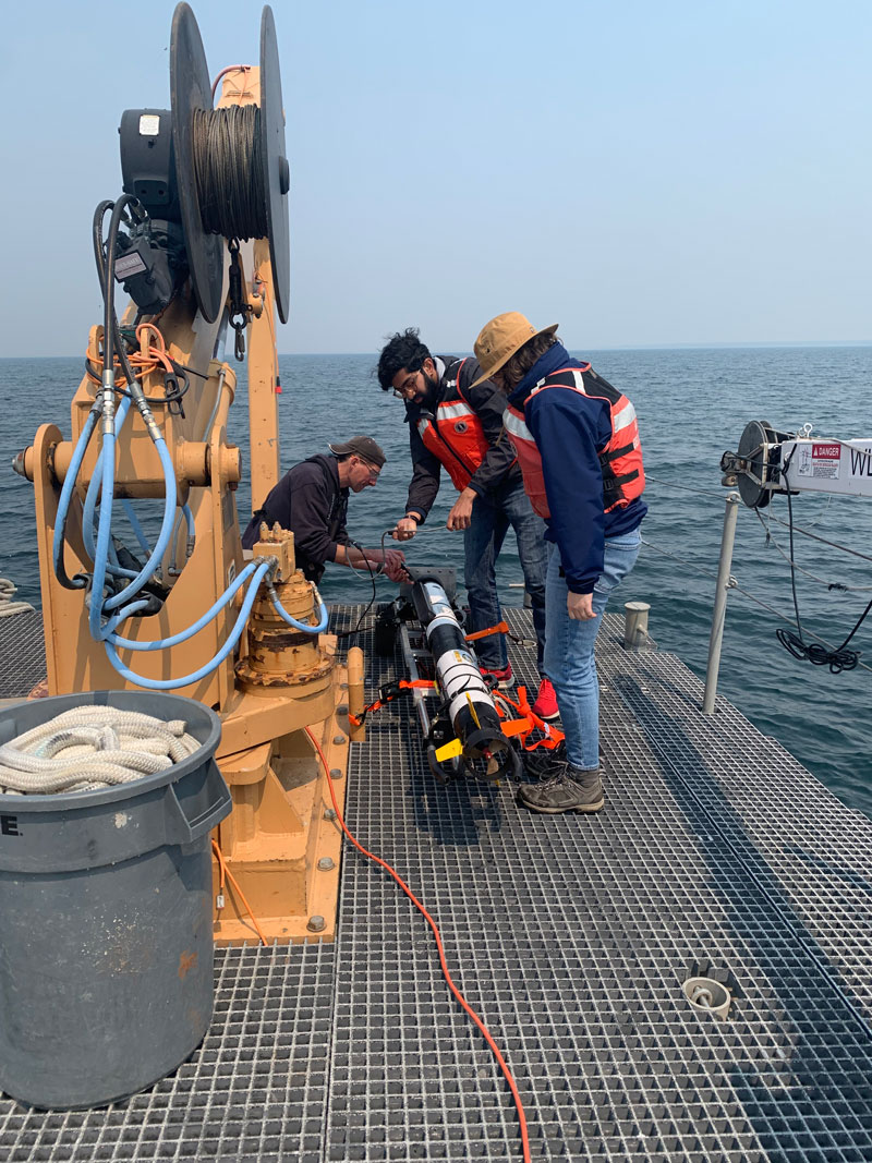 Michigan Technological University engineer, Chris Pinnow, and University of Michigan graduate students, Advaith Sethuraman and Anja Sheppard, prepare the IVER autonomous underwater vehicle for deployment.