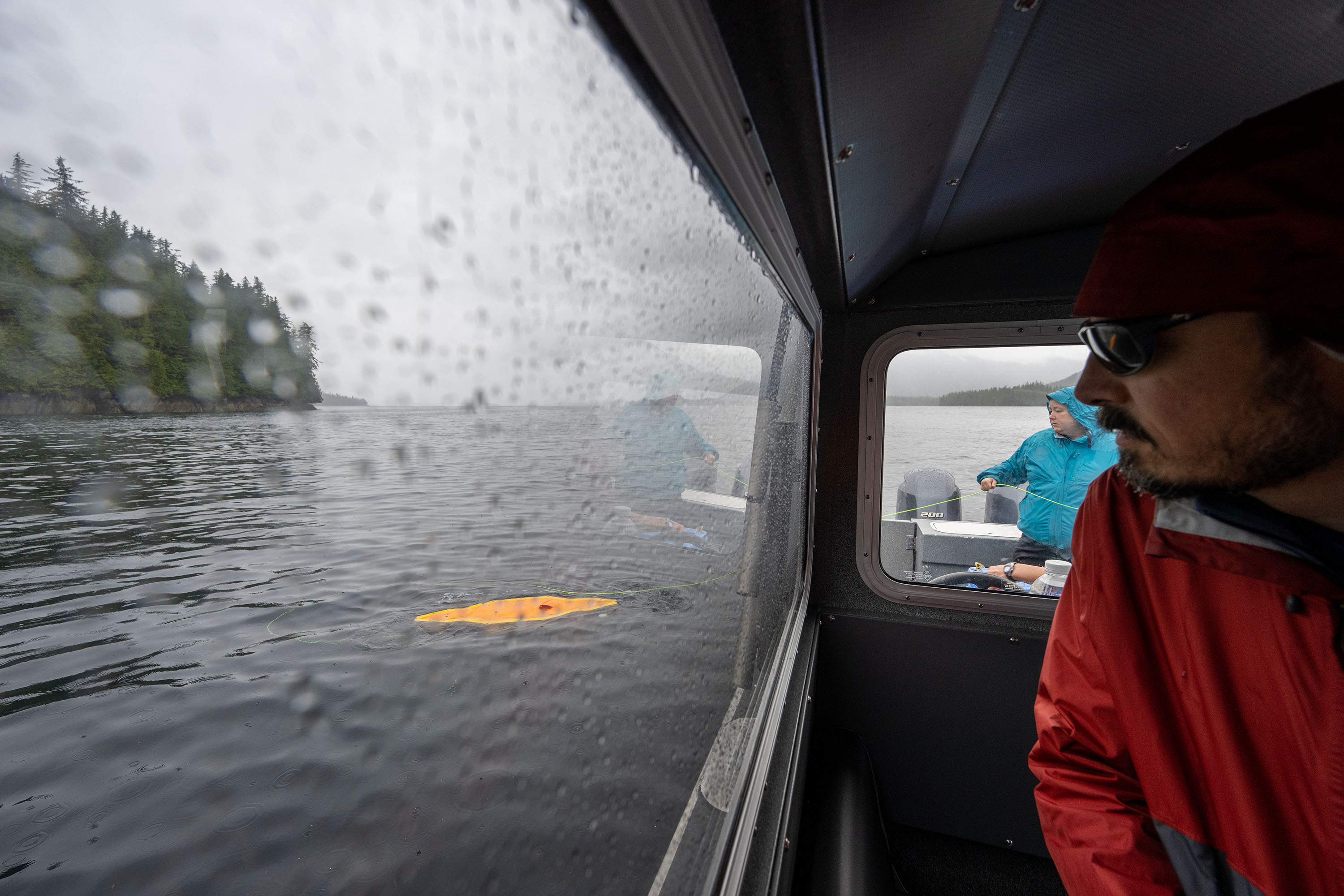 Marine archeologist Dr. Kelly Monteleone, rear, manages hundreds of meters of green fiber optic cable from the aft deck of the Showtime fishing vessel while Sunfish chief technology officer Dr. Kristof Richmond finishes pre-dive testing on autonomous underwater vehicle SUNFISH during 2023 field work for the Our Submerged Past project. While SUNFISH can operate autonomously, the team uses the thin tether to connect the robot to a station on the boat where operators can remotely supervise missions and redirect it as necessary.