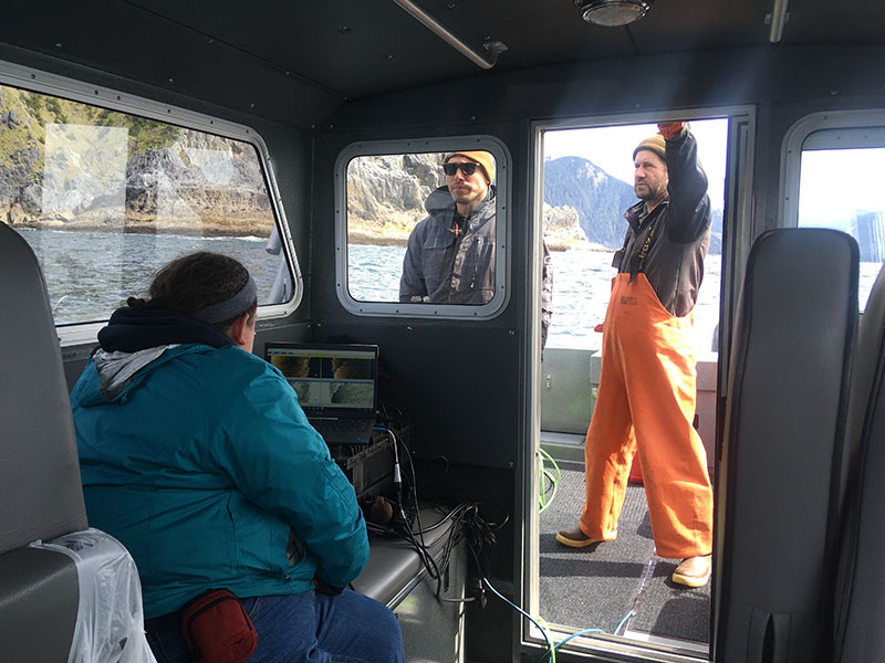 The Our Submerged Past survey team at work. Dr. Kelly Monteleone reviewing sidescan sonar data as it is collected, Roby Medina driving Fishing Vessel Showtime using the kicker or small engine, and Brant Baxter watching the GPS and bottom sounder while on deck.