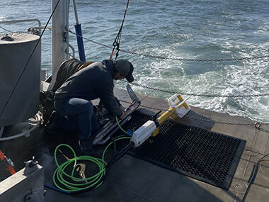 A project team member checks the connection between the side-scan sonar (left) and the magnetometer (right). The instruments were connected so the team only had to manage one tether.