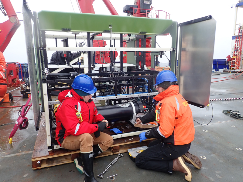 Grace Cawley and Hannah Kepner (left to right) prepare the In-Situ Ichthyoplankton Imaging System Deep-Focus Particle Imager (ISIIS-DPI) for deployment. This specialized camera system is used to image and study plankton in its natural environment.