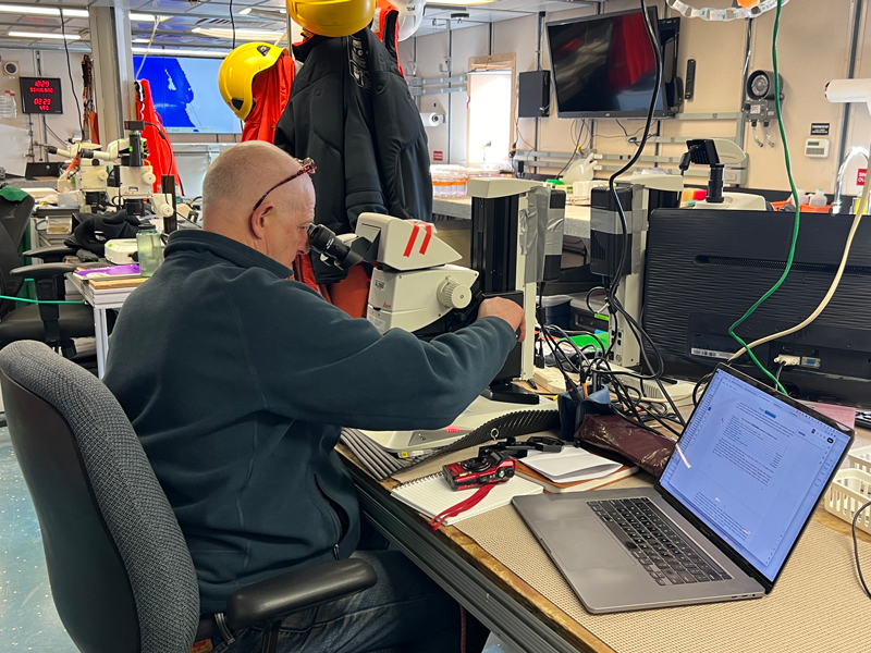 Allen Collins studies a jellyfish under the microscope in the lab of Research Vessel Sikuliaq during the Exploring Pelagic Biodiversity of the Gulf of Alaska and the Impact of Its Seamounts expedition.