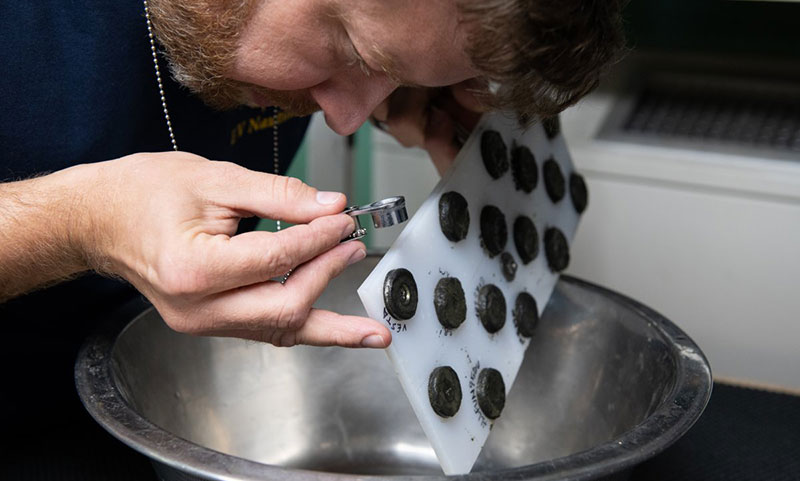 NASA scientist Dr. Marc Fries examines early sample returns attached to the magnetic board. Credit: OET