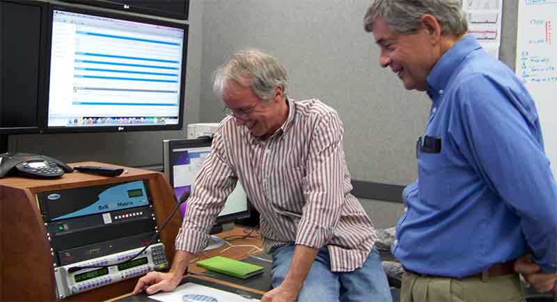 Voice communication between <em>Okeanos Explorer</em> and shore-side ECC’s uses another technology borrowed from the broadcast industry, an IP-enabled intercom system. The intercom system leverages the <em>Okeanos Explorer’s </em>Internet connectivity to connect all of the ship-based and shore-bases intercom units into a single system. This allows all participants, regardless of location to easily communicate with all other participants. Here, scientists at the Seattle ECC communicate with participants on the ship and at the Jakarta ECC.