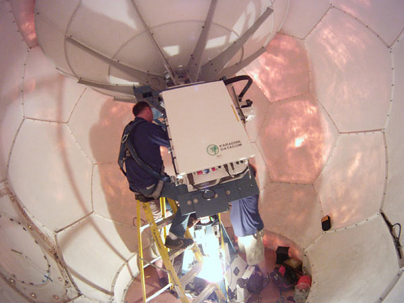 Technicians work on the satellite antenna in the VSAT dome.