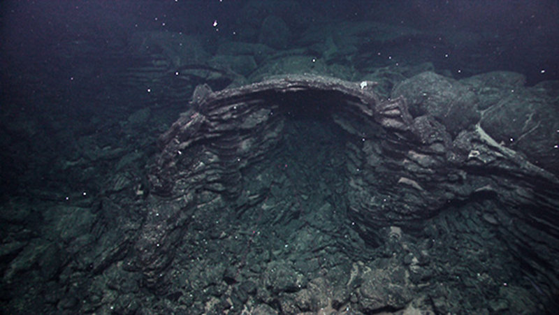 An archway formed by lava pillars supporting a remnant of intact lobate lava flow crust within a large collapsed lava lake.