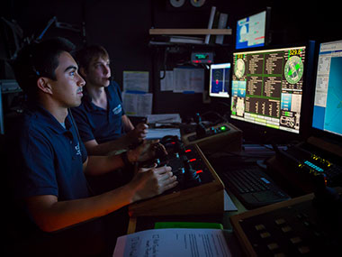 Anthony Sylvester (left) pilots ROV Deep Discoverer for the first time while Bobby Mohr watches from the navigator position.