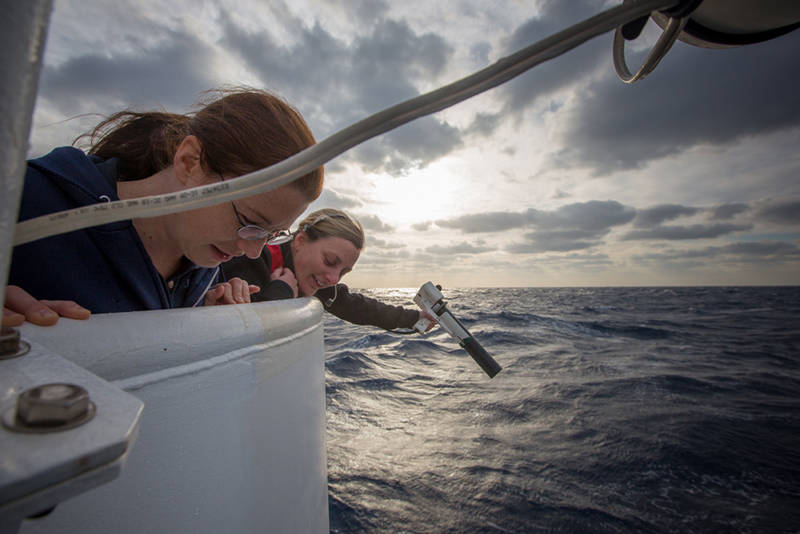 Mapping operations were conducted today following cancellation of the remotely operated vehicle dive due to heavy seas. Here, Mapping Team Lead Meme Lobecker conducts an XBT, or expendably bathythermograph cast, to measure temperature down to 760 meters in order to correct mapping data for water column variability. Due to the high sea state and heavy winds, she is accompanied by a team member (Expedition Coordinator, Kelley Elliott) to ensure safe operations. They are watching the incredibly thin copper wire as it pays out from the XBT to ensure it doesn’t contact the ship and corrupt the data.