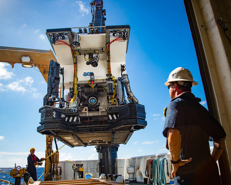 Chief Bosun Jerrod Hozendorf watches as ROV Deep Discoverer (D2) is deployed from the aft deck of NOAA Ship Okeanos Explorer. D2’s powerful lighting, high definition camera and newly installed sample collection equipment (drawers, boxes, an advanced manipulator, and positionable illumination system) are visible.