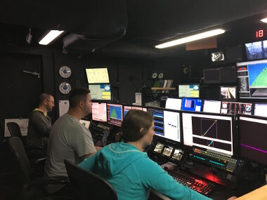 The NOAA Ship Okeanos Explorer mapping team hard at work in the control room. During the 60+ hours of transit, the ship is continuously collecting data with three different types of sonar.