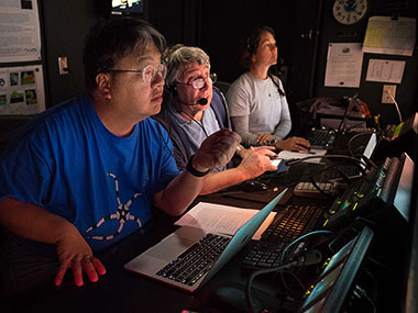 Onboard science leads Drs. Chris Mah and Chris Kelley and NOAA Educational Partnership Program Intern Nikola Rodriguez discuss and take a closer look at deepwater habitats explored with remotely operated vehicle Deep Discoverer on Horizon Guyot. 