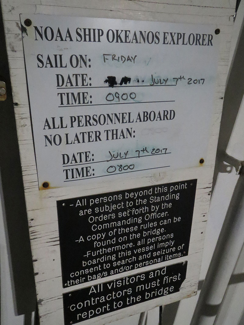 Picture of the sailing board on NOAA Ship Okeanos Explorer showing the date and time of departure for the next cruise and the time by which all personnel who are sailing need to be physically on board the ship to sail. Cruise EX-17-06 departed on time at 0900 on Friday, July 7, as planned.