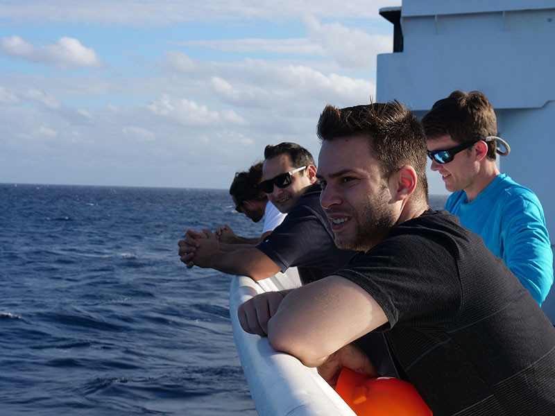 Mike Smith (CCOM/UNH), Robert Mills (JASCO), Lt. Nick Pawlenko (OER), and Patrick Bordner (Navy) search the horizons during hydrophone recovery. The array was triggered from its mooring using an acoustic signal and took about an hour to float up to the surface.