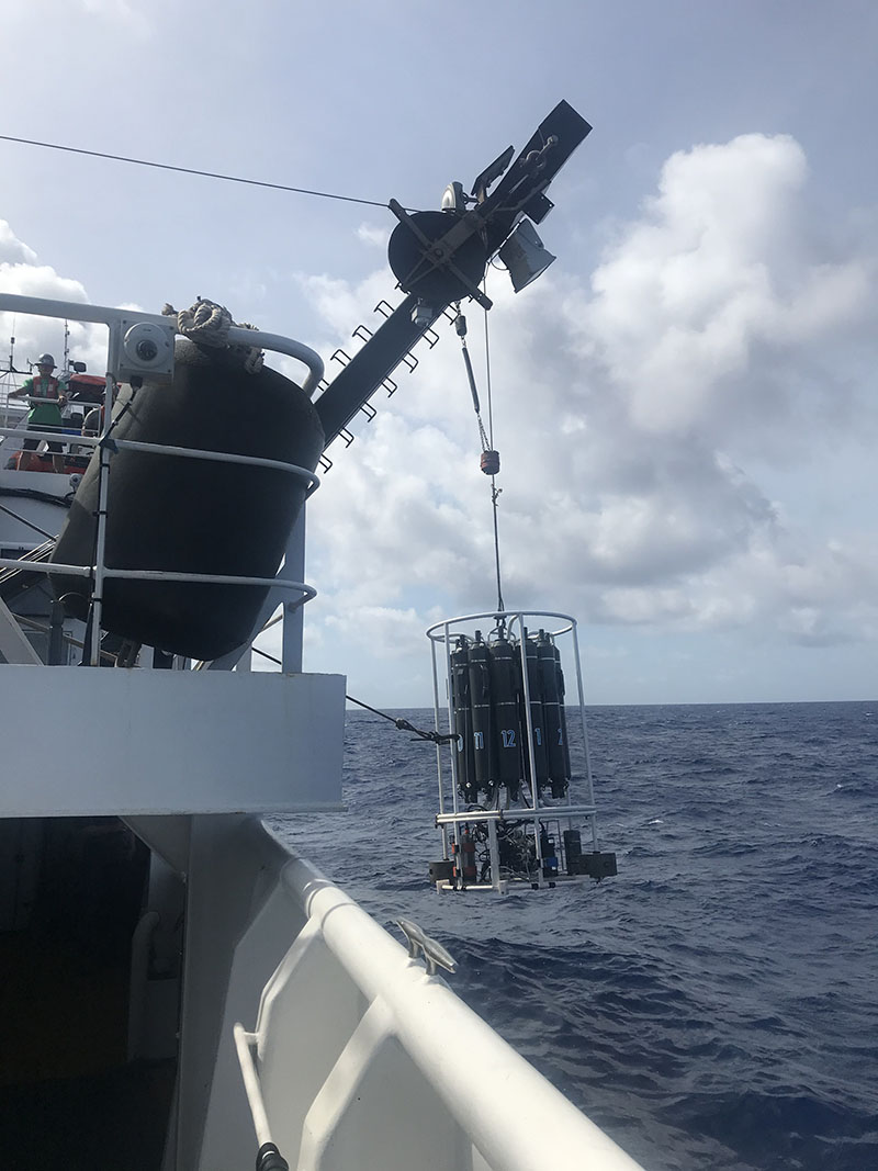 CTD rosette being lifted out of the ocean via cable and a hook from the starboard side of NOAA Ship Okeanos Explorer.