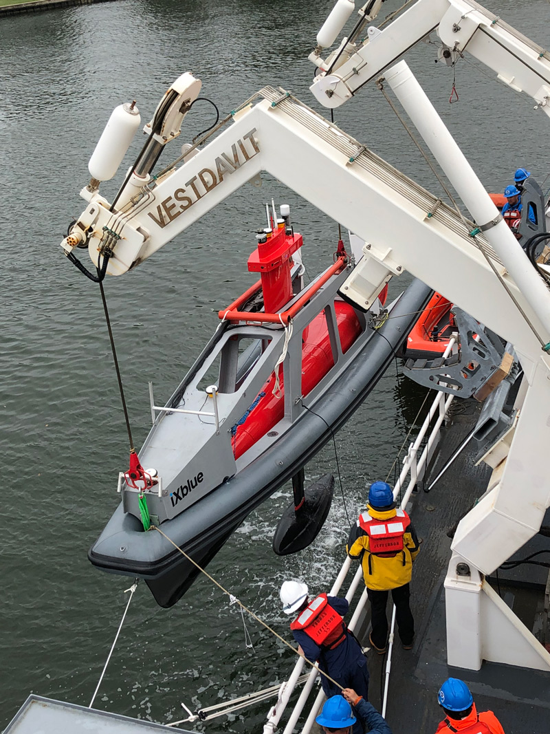 A DriX unmanned surface vehicle, within its docking system, is seen being fitted by engineers into the davits of NOAA Ship Thomas Jefferson