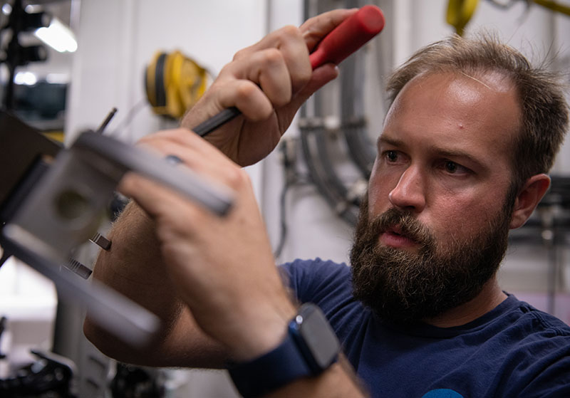 Jeff Laning, an Electrical Engineer with the Global Foundation for Ocean Exploration, works to fix the claw of the manipulator arm on remotely operated vehicle Deep Discoverer. The claw is a key tool for collecting samples from the seafloor, so getting it back in working order was important to meeting the objectives of Windows to the Deep 2021. Image courtesy of NOAA Ocean Exploration, Windows to the Deep 2021.
