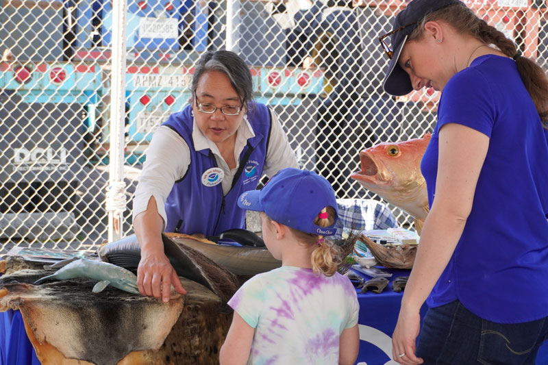 Staff from NOAA Fisheries Alaska Fisheries Science Center answer questions from a young explorer during the port event that took place in Seattle, Washington, following the end of the 2023 Shakedown + EXPRESS West Coast Exploration expedition.