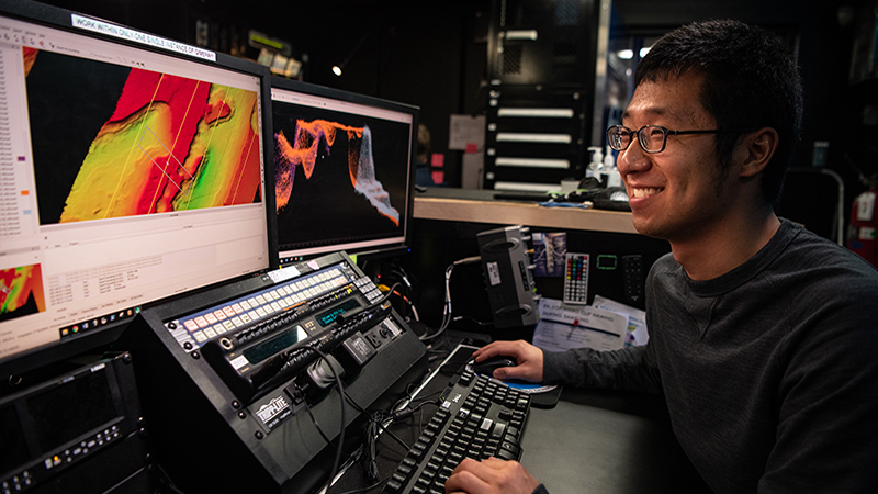 Explorer-in-training Edward Kim works to process multibeam bathymetry data collected during an expedition on NOAA Ship <i>Okeanos Explorer</i>. Three explorers-in-training will join the Beyond the Blue: Papahānaumokuākea Mapping 1 expedition in this role.