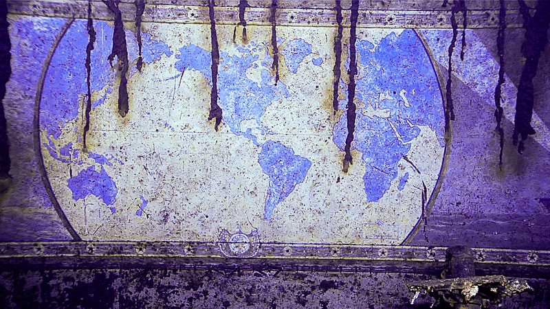 A vintage world map with blue continents and cream oceans, marked by dark vertical streaks.