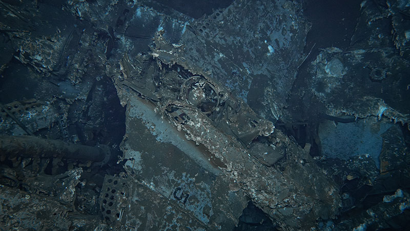 Underwater bomber wreck with corroded metal and marine growth.