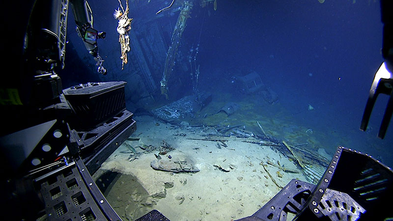 Underwater shipwreck scene with debris and parts of a remotely operated vehicle.