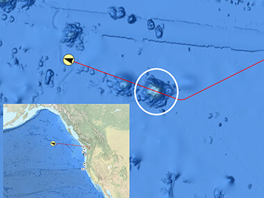 A screenshot of NOAA Ocean Exploration’s Okeanos Explorer - Live Operations Map showing the seamount mapped during the Seascape Alaska 1: Aleutians Deepwater Mapping expedition circled in white. The red line shows the Okeanos Explorer’s trackline, and the yellow circle with a black arrow shows the ship’s location at the time of the screenshot. The inset screenshot shows the ship’s position relative to the west coast of the United States and Canada.