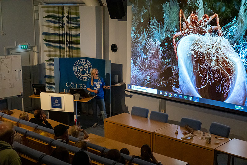 Lova Eveborn, science communicator, giving a presentation about a coral dive in the auditorium.