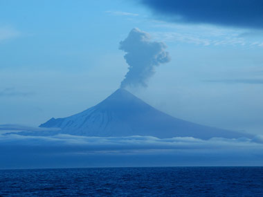 Shishaldin Volcano seen here erupting on July 14, 2023, at an alert level of “watch.” This eruption intensified, triggering an alert level of “red/warning” on July 18, 2023.” Image courtesy of Lee Cooper, onboard the Canadian Coast Guard icebreaker Sir Wilfrid Laurier.