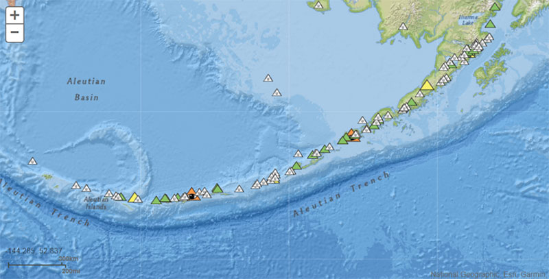 Map showing the location of the Alaska-Aleutian subduction zone, Aleutian trench, and location of volcanos on July 22, 2023. Colored triangles are monitored by the Alaska Volcano Observatory. Orange triangles are monitored volcanoes listed at a of “watch.”