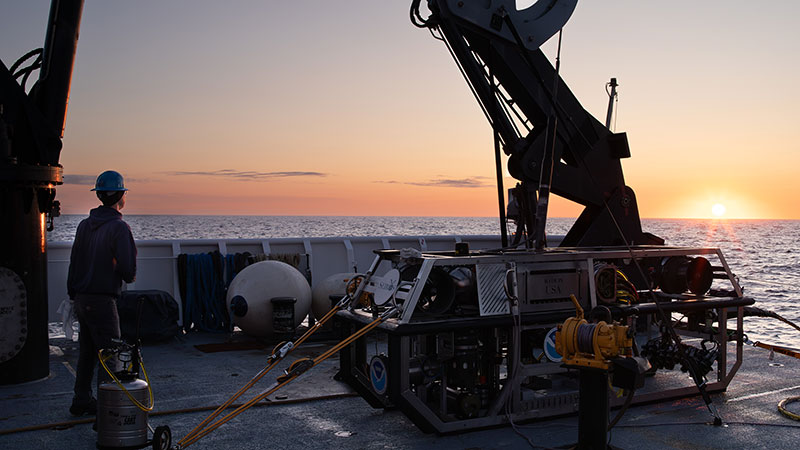 The sunrises over the back deck of NOAA Ship Okeanos Explorer and remotely operated vehicle Seirios.