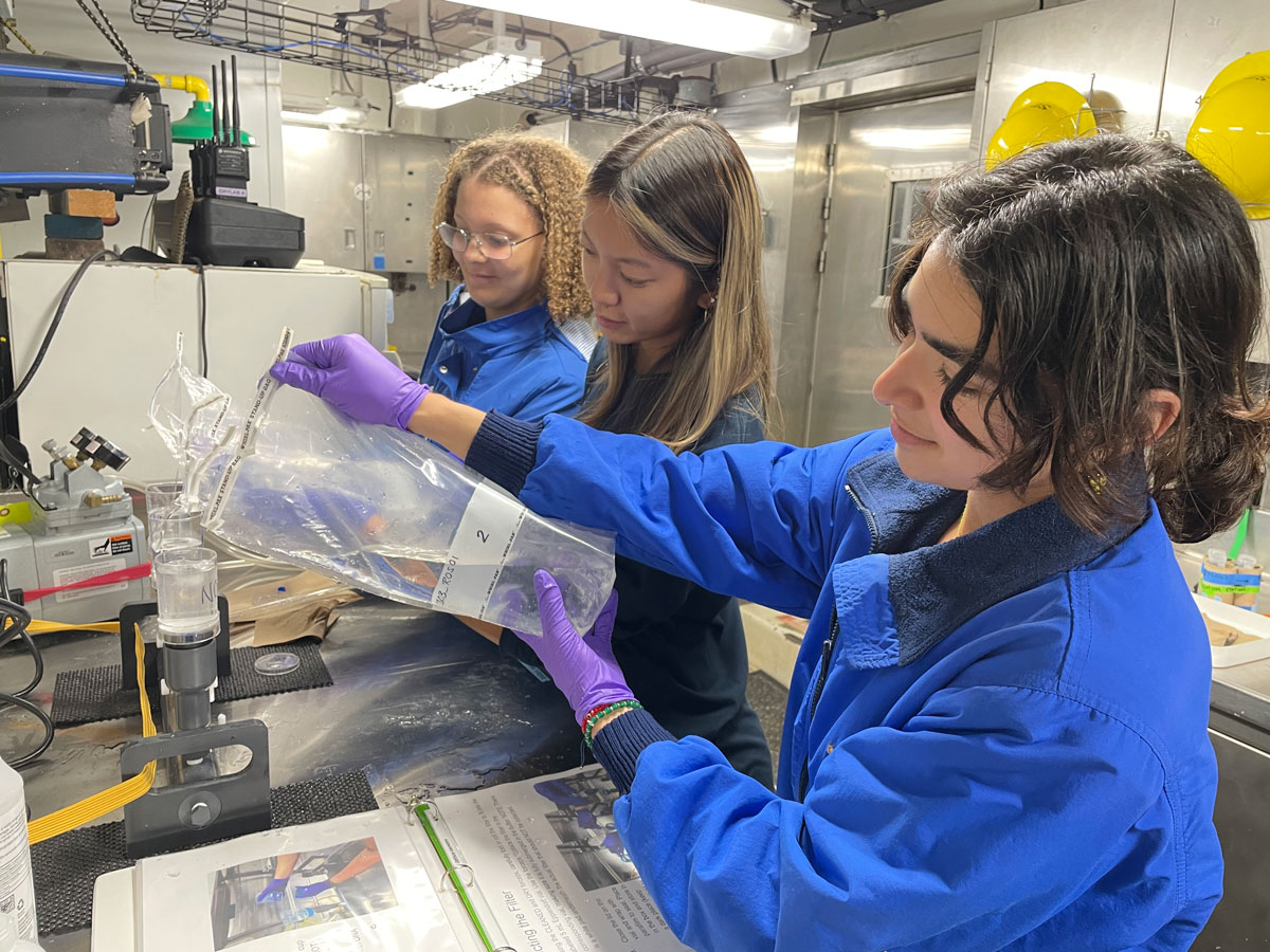 Explorers-in-Training Rebecca Ruiz, Rose Leeger, and Ranna Zahabi filter water samples for environmental DNA collection during the Seascape Alaska 2: Aleutians Deepwater Mapping expedition.