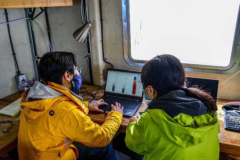 Principal investigator Wu-Jung Lee and research assistant Linda Nguyen analyze the data coming in from the ship’s mounted echosounder. The graphs on their screens are called echograms and can be used to identify layers of small organisms in the water column. Image courtesy of Coordinated Simultaneous Physical-Biological Sampling Using ADCP-Equipped Ocean Gliders.