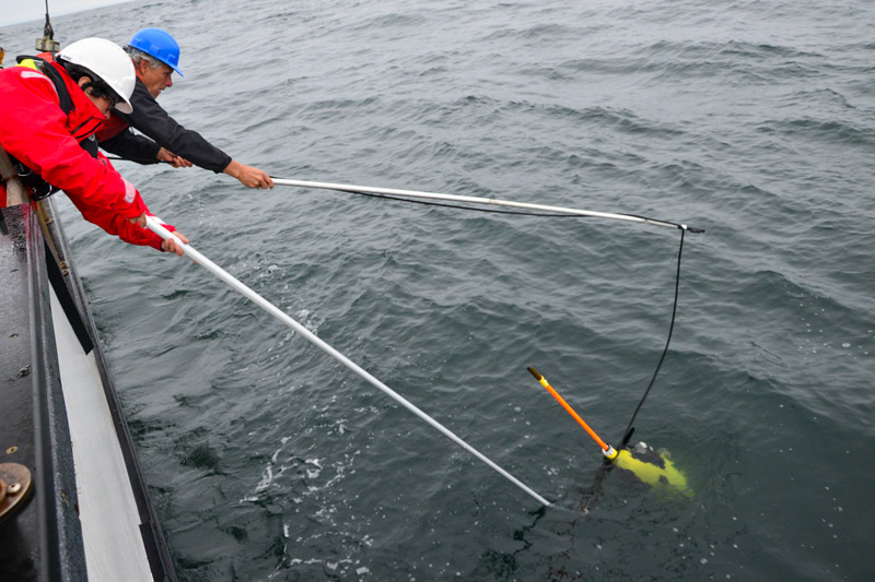 As the Seaglider is lined up alongside the boat, captain Eric Boget and engineer Christina Ramirez work together to lasso the vehicle before it drifts away. Weighing over 57 kilograms (125 pounds), Seagliders require teamwork for safe handling. In order to retrieve this glider, Eric and Christina must snag their lassos around the wings, attach the glider to a crane, and lift it onto the deck where it can be stowed for the long journey back to shore. 