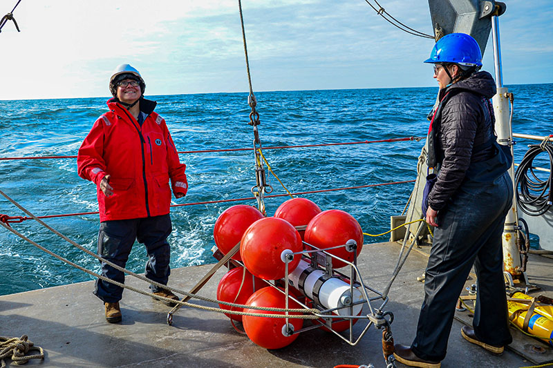 The Coordinated Simultaneous Physical-Biological Sampling Using ADCP-Equipped Ocean Gliders expedition team prepares to deploy a moored acoustic echosounder. This instrument, attached to a heavy weight, will drop to the seafloor where it will use sound to explore the water column. The four orange floats attached to the echosounder will help it float to the water’s surface when it is time to recover the system.