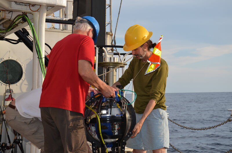 A member of the glider team helps a member of the Driftcam team move the Driftcam after it was retrieved from sea.
