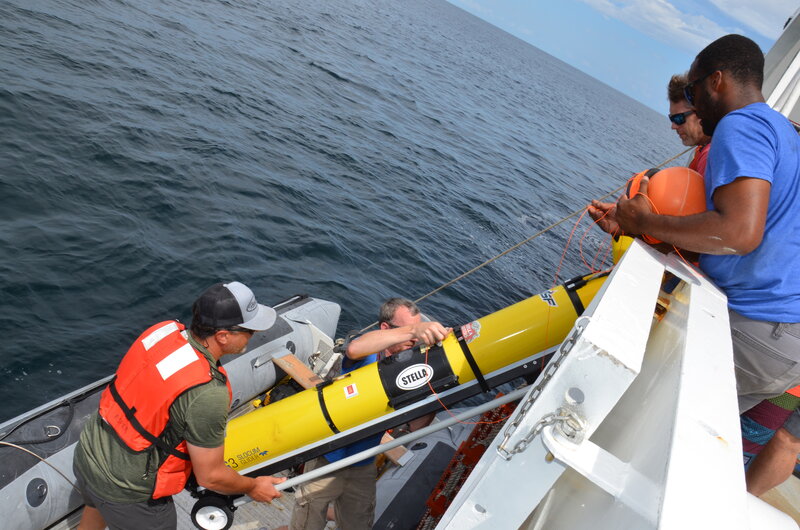 The glider team and ship’s crew work to transfer the glider from the R/V Point Sur to a small boat for deployment.
