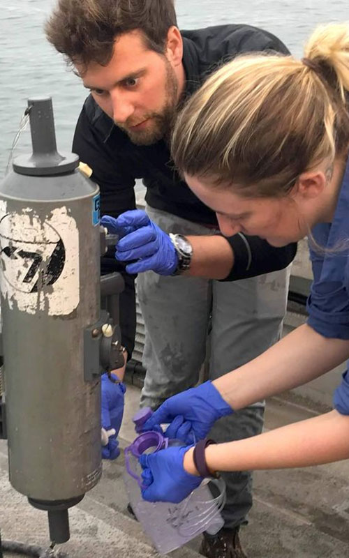Researchers Adam Wall and Teia Schweizer collecting a water sample.