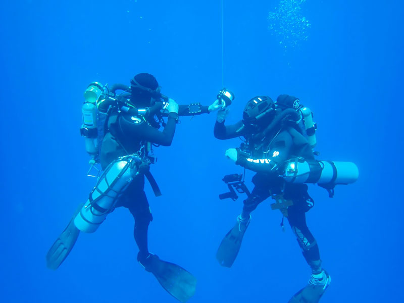 Technical divers conducting a safety stop while ascending to the surface after diving to depths of 61 meters (200 feet) in search of a lost World War II aircraft.