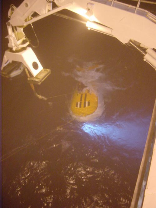 A Mir swimmer attaches the crane from the Keldysh to the top of the submersible. The crane will then lift the Mir out of the water.