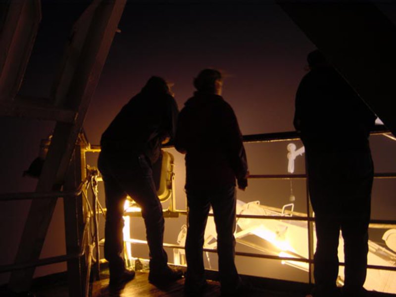 As the Mirs finish their dives for the day, three silhouettes watch from the sixth deck as the submersibles are brought back to the Keldysh.