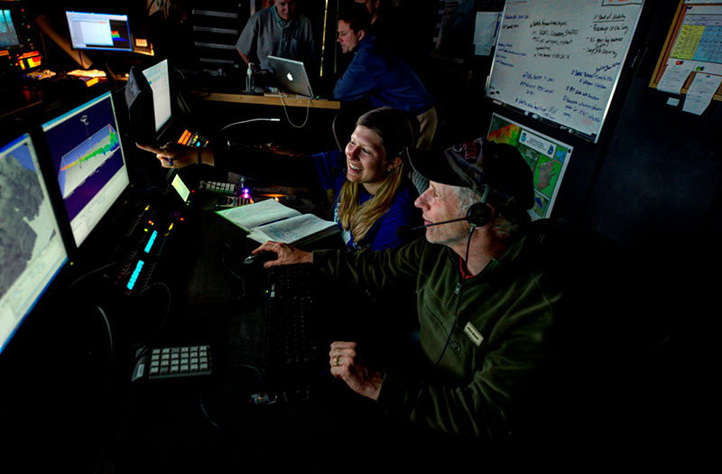 Intern Meredith Myers and marine ecologist Dave Packer viewing canyon data using Fledermaus software in the Okeanos Explorer control room.